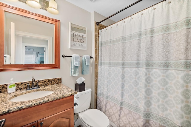 bathroom featuring toilet, vanity, and curtained shower