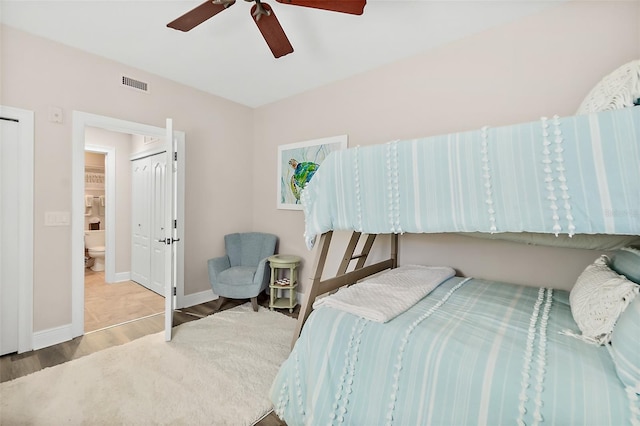 bedroom with ceiling fan, ensuite bathroom, and hardwood / wood-style floors