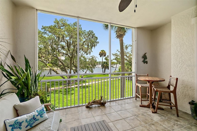 sunroom / solarium with ceiling fan and a water view