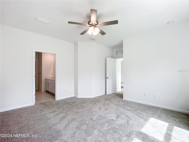 unfurnished bedroom with light colored carpet, ensuite bath, and ceiling fan