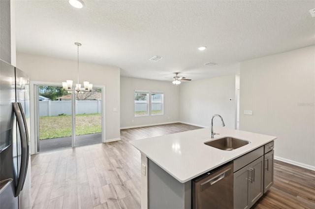 kitchen with appliances with stainless steel finishes, light hardwood / wood-style flooring, an island with sink, pendant lighting, and sink