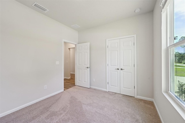 unfurnished bedroom with light carpet and a closet