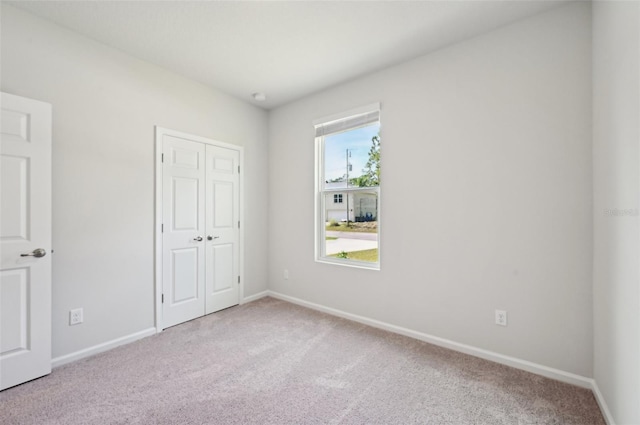 unfurnished bedroom featuring light carpet and a closet