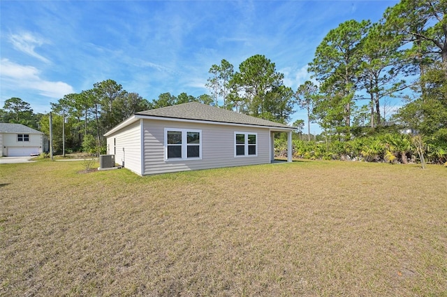 back of property with central AC unit and a yard