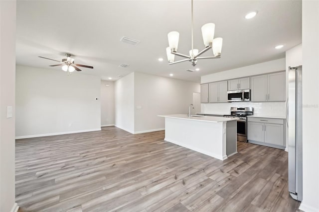 kitchen with a kitchen island with sink, gray cabinetry, decorative light fixtures, sink, and appliances with stainless steel finishes