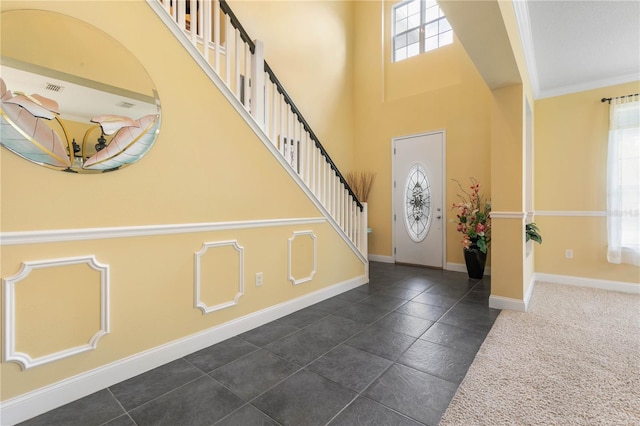 foyer entrance with crown molding, dark tile patterned flooring, and a wealth of natural light