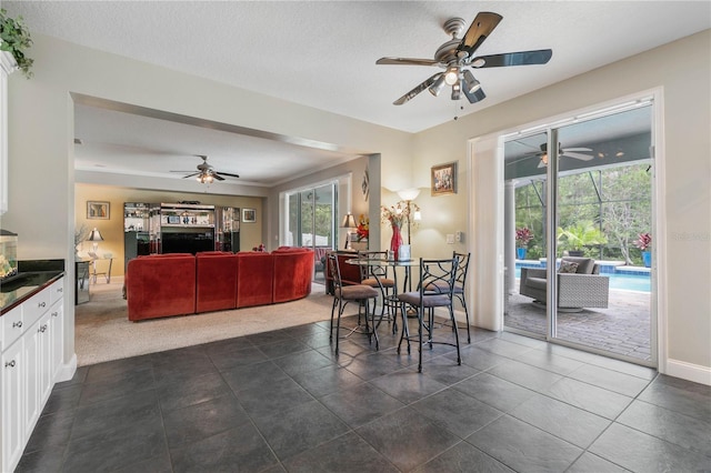 dining room with a textured ceiling, ceiling fan, and dark tile patterned flooring