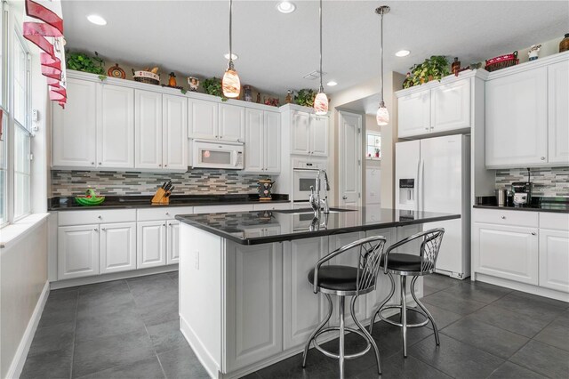 kitchen with white cabinetry, sink, white appliances, and dark tile patterned flooring