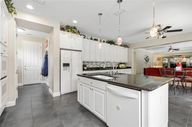 kitchen with white cabinetry, ceiling fan, white appliances, sink, and a center island with sink