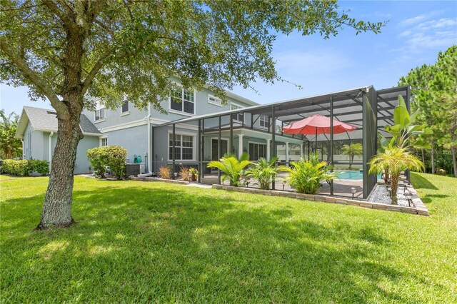 rear view of property with a patio, a yard, and a lanai