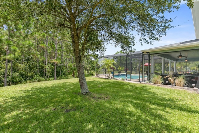 view of yard featuring ceiling fan and glass enclosure