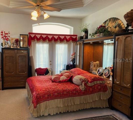 carpeted bedroom featuring a tray ceiling and ceiling fan