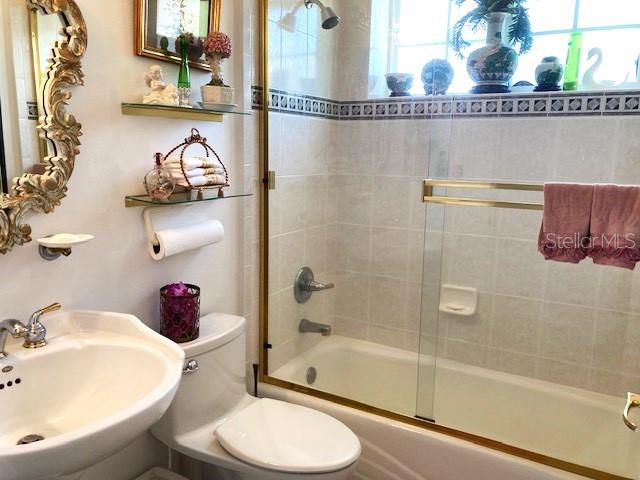 full bathroom with sink, enclosed tub / shower combo, and toilet