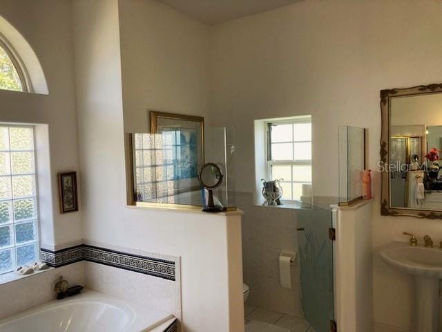 bathroom featuring tile patterned flooring, a tub to relax in, and toilet