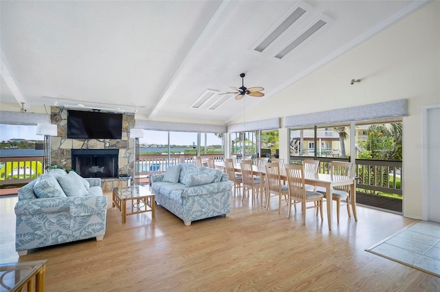 living room with beamed ceiling, a fireplace, light wood-type flooring, and ceiling fan