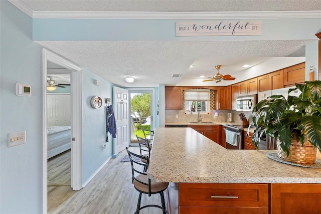 kitchen featuring a textured ceiling, ceiling fan, backsplash, and stainless steel appliances