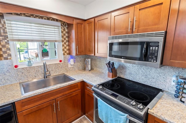 kitchen featuring range with electric stovetop, backsplash, light stone counters, and sink