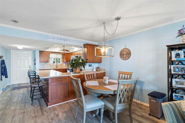 dining room featuring ceiling fan, a textured ceiling, hardwood / wood-style flooring, and ornamental molding