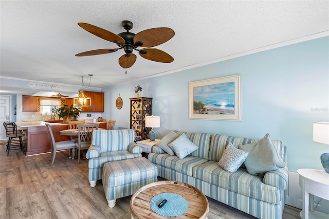 living room featuring light hardwood / wood-style floors, a textured ceiling, crown molding, and ceiling fan