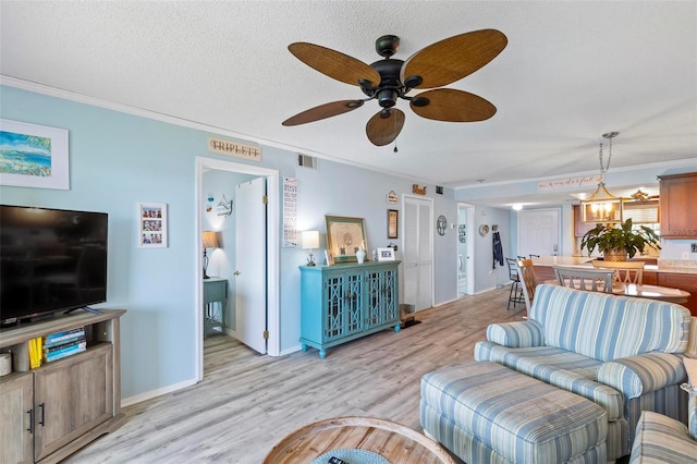 living room with a textured ceiling, ceiling fan, light wood-type flooring, and crown molding