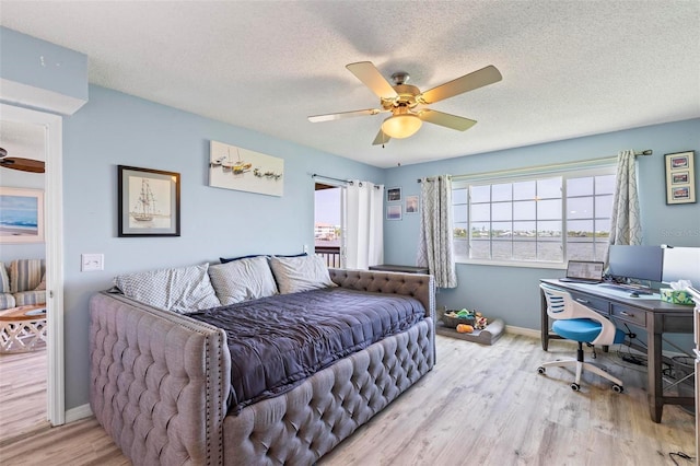 bedroom with light hardwood / wood-style floors, a textured ceiling, and ceiling fan