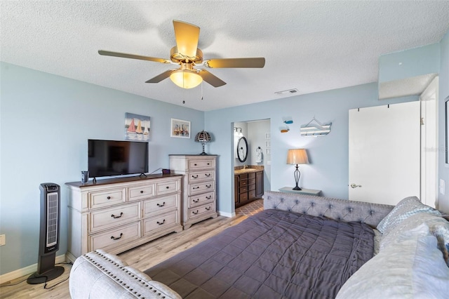 bedroom with a textured ceiling, light hardwood / wood-style flooring, ensuite bath, and ceiling fan