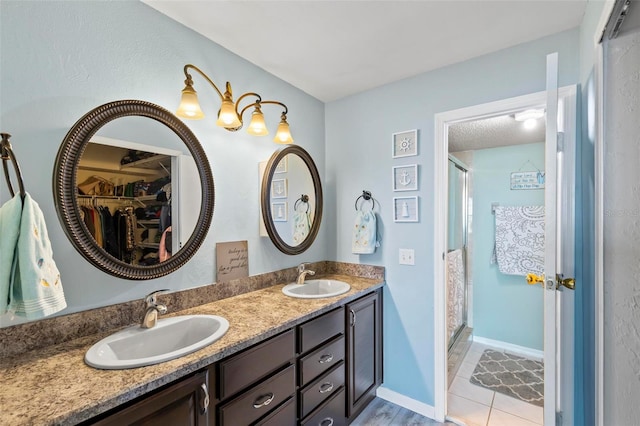 bathroom featuring dual vanity, a shower with door, and tile patterned floors