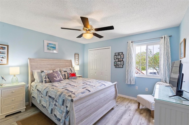 bedroom with ceiling fan, a textured ceiling, light hardwood / wood-style flooring, and a closet