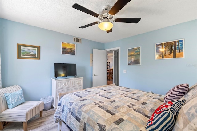 bedroom featuring a textured ceiling, ceiling fan, and light wood-type flooring