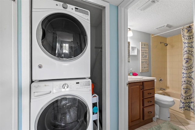 laundry room featuring light tile patterned flooring, sink, a textured ceiling, and stacked washer / drying machine