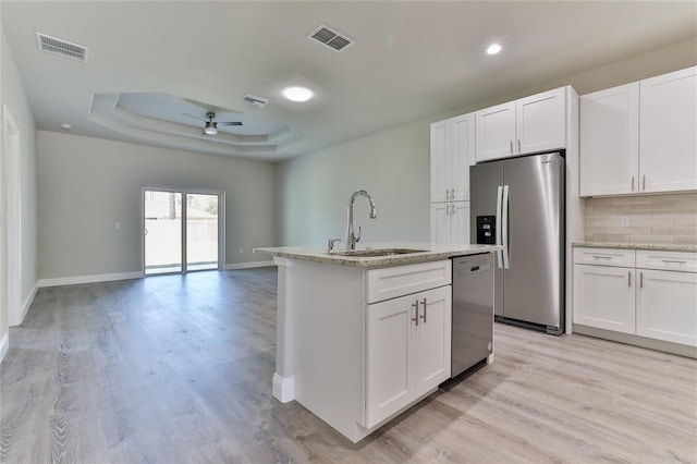 kitchen with light hardwood / wood-style flooring, stainless steel appliances, sink, ceiling fan, and a raised ceiling