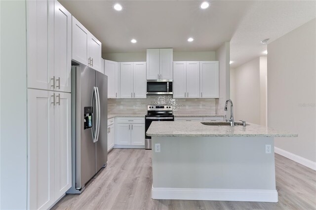 kitchen with appliances with stainless steel finishes, light wood-type flooring, decorative backsplash, and sink