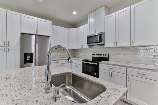 kitchen with sink, decorative backsplash, stainless steel appliances, and white cabinetry