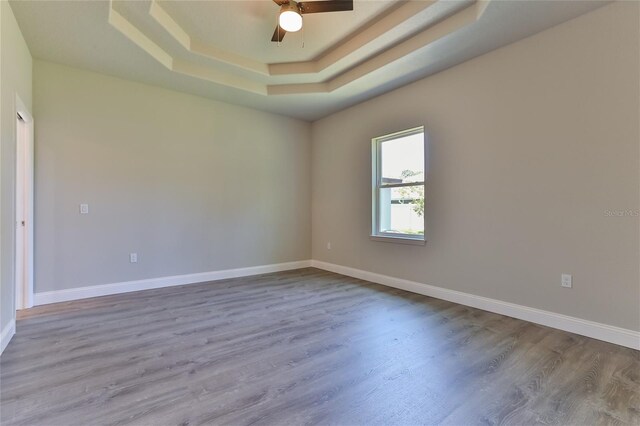 spare room with hardwood / wood-style flooring, a raised ceiling, and ceiling fan