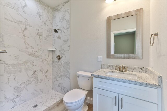 bathroom featuring toilet, vanity, and a tile shower