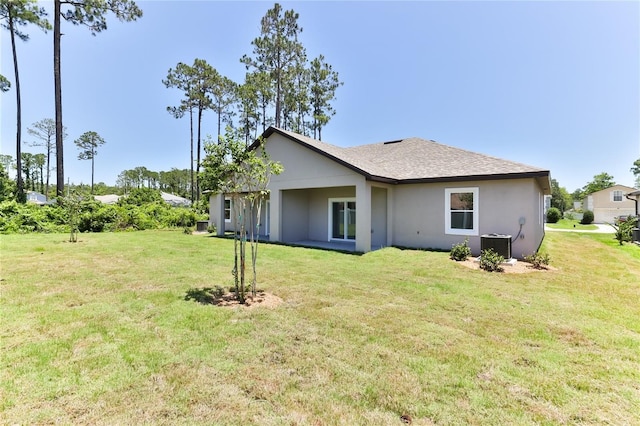 rear view of house featuring central AC and a lawn