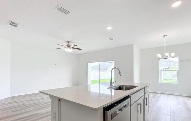 kitchen featuring light countertops, visible vents, stainless steel dishwasher, a sink, and an island with sink