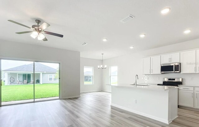 kitchen featuring stainless steel appliances, a sink, white cabinetry, hanging light fixtures, and light countertops