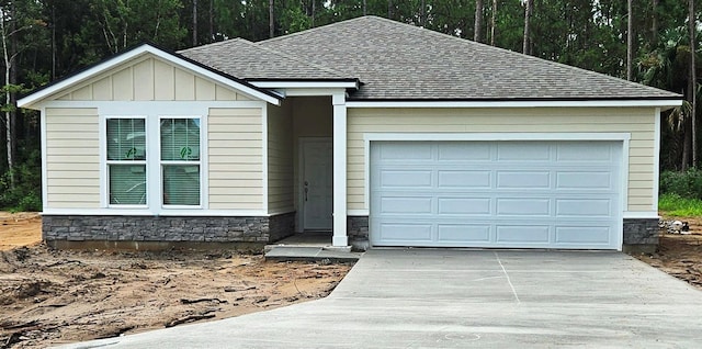 ranch-style home featuring a shingled roof, an attached garage, board and batten siding, stone siding, and driveway