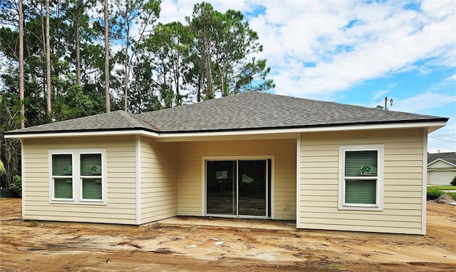 rear view of house featuring roof with shingles