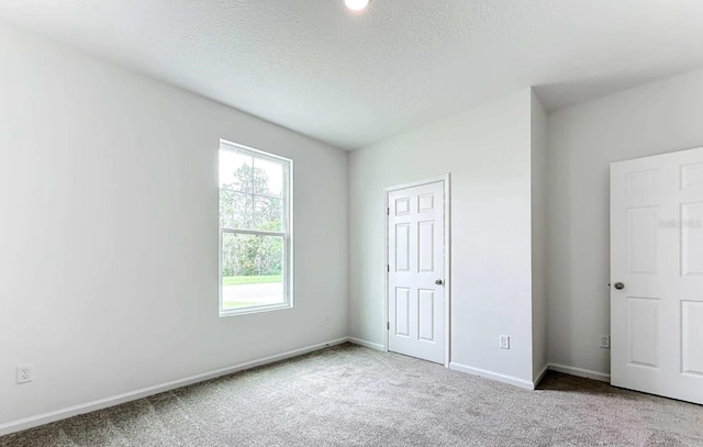 unfurnished bedroom featuring a textured ceiling, baseboards, and carpet flooring