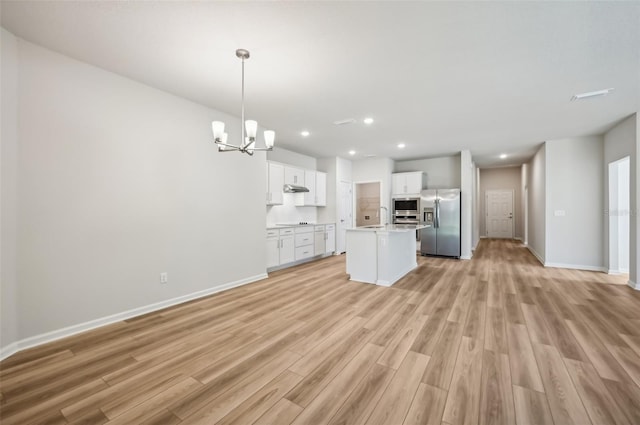 kitchen featuring sink, white cabinetry, decorative light fixtures, appliances with stainless steel finishes, and an island with sink