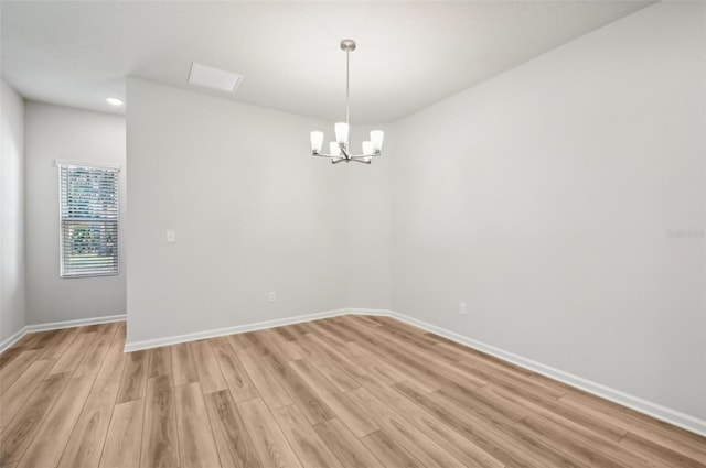 spare room with a notable chandelier and light hardwood / wood-style floors