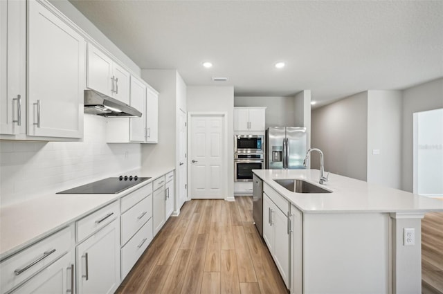 kitchen featuring sink, stainless steel appliances, an island with sink, and white cabinets