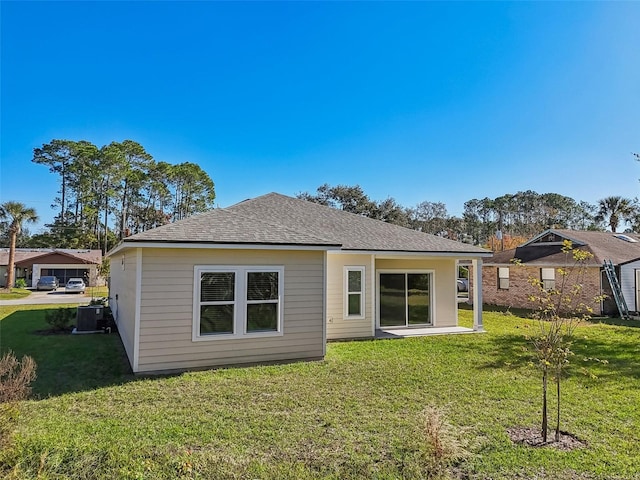 rear view of property with a lawn and central air condition unit