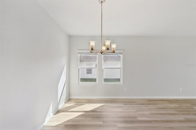 unfurnished dining area featuring a notable chandelier and light hardwood / wood-style flooring