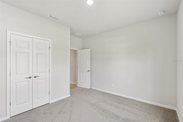 unfurnished bedroom with a closet and light colored carpet