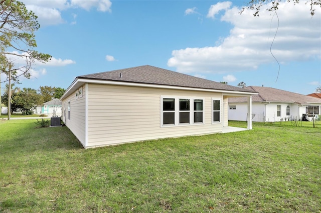 back of house featuring central air condition unit and a lawn