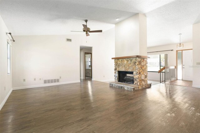 unfurnished living room featuring a stone fireplace, a textured ceiling, hardwood / wood-style flooring, and ceiling fan