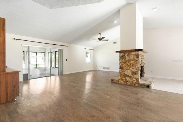 unfurnished living room featuring a fireplace, ceiling fan, dark hardwood / wood-style flooring, vaulted ceiling, and a textured ceiling